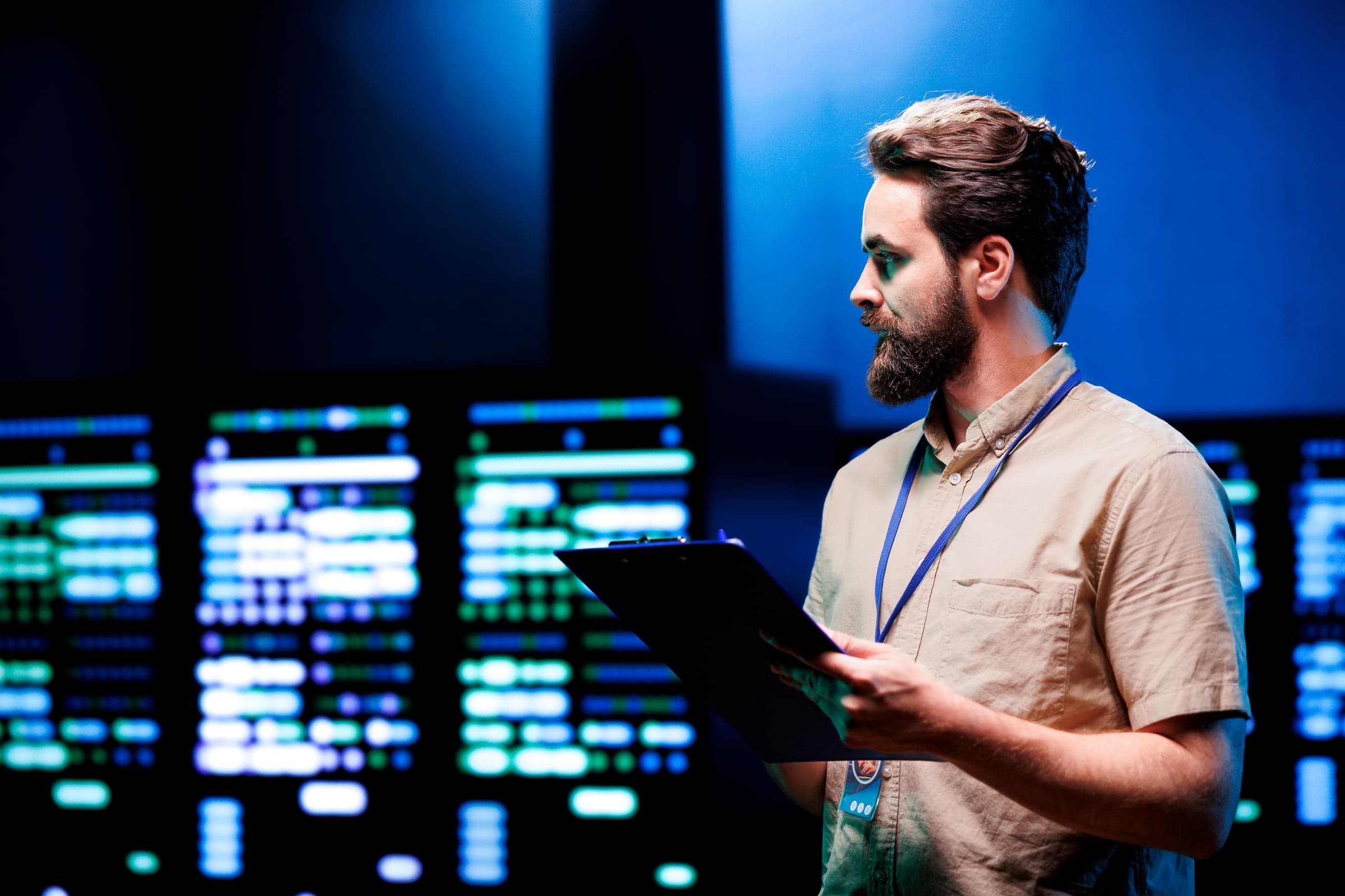 IT technician with a clipboard in front of server cabinets with status indicators